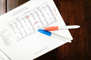 Documents comptables d'une association État financier annoté au surligneur, posé sur une table en bois avec deux marqueurs